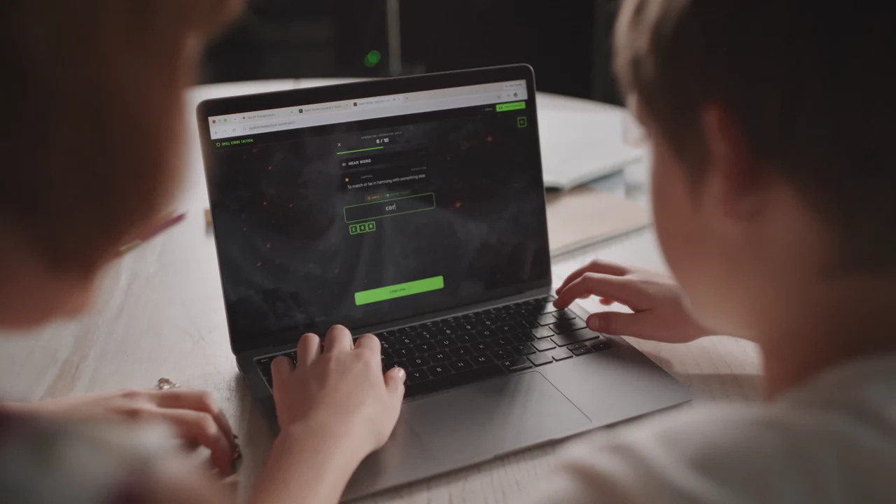 Over-the-shoulder view of Silas using Spell Strike on a laptop with Kelly